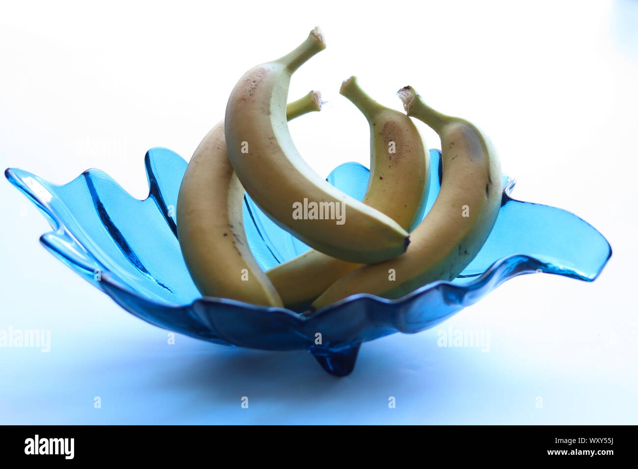 Seule la banane dans un bol en verre décoratif bleu turquoise contre fond blanc Banque D'Images