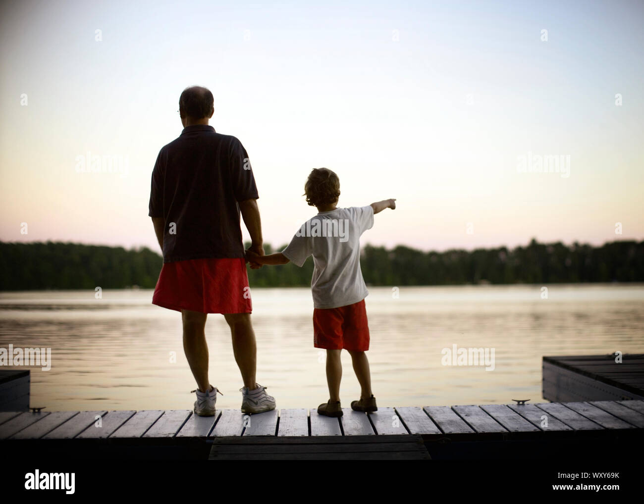 Père et fils se tenir sur un quai au coucher du soleil Banque D'Images