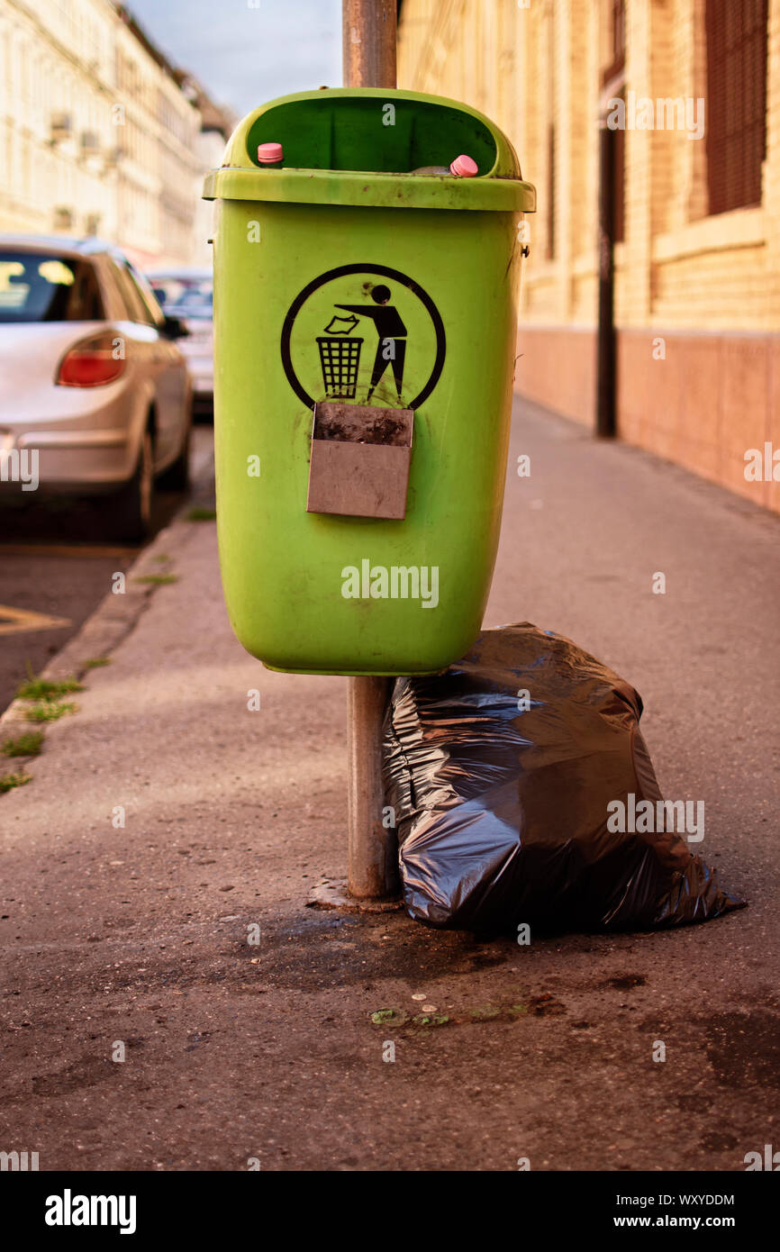 Poubelle verte sale de la rue avec un sac poubelle noir couché à côté  d'elle Photo Stock - Alamy
