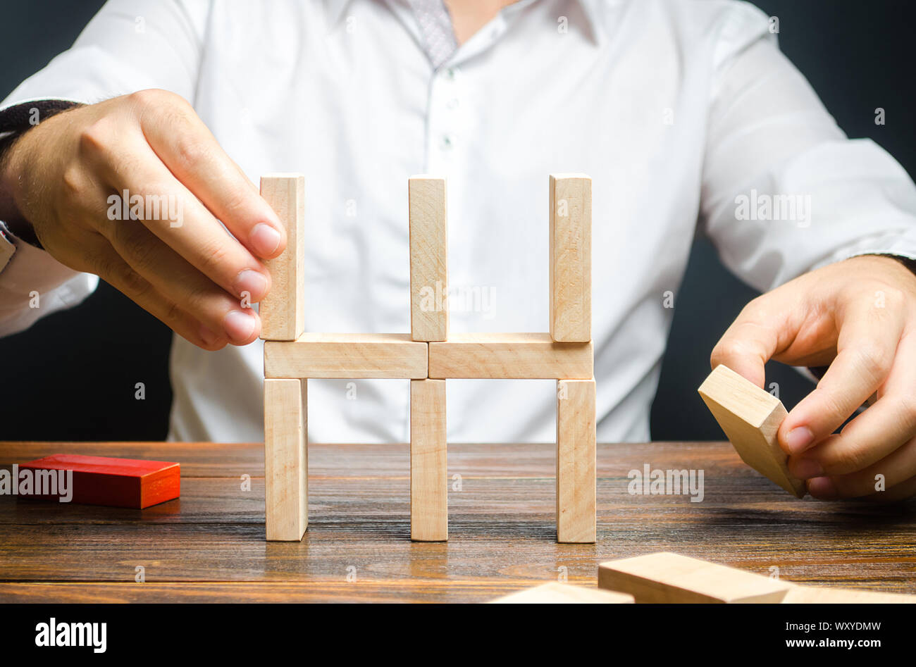 Businessman recueille une chambre des dominos. Création conceptuelle d'une nouvelle entreprise ou le démarrage, mettre en place des processus. Construction d'un immeuble d'buil Banque D'Images