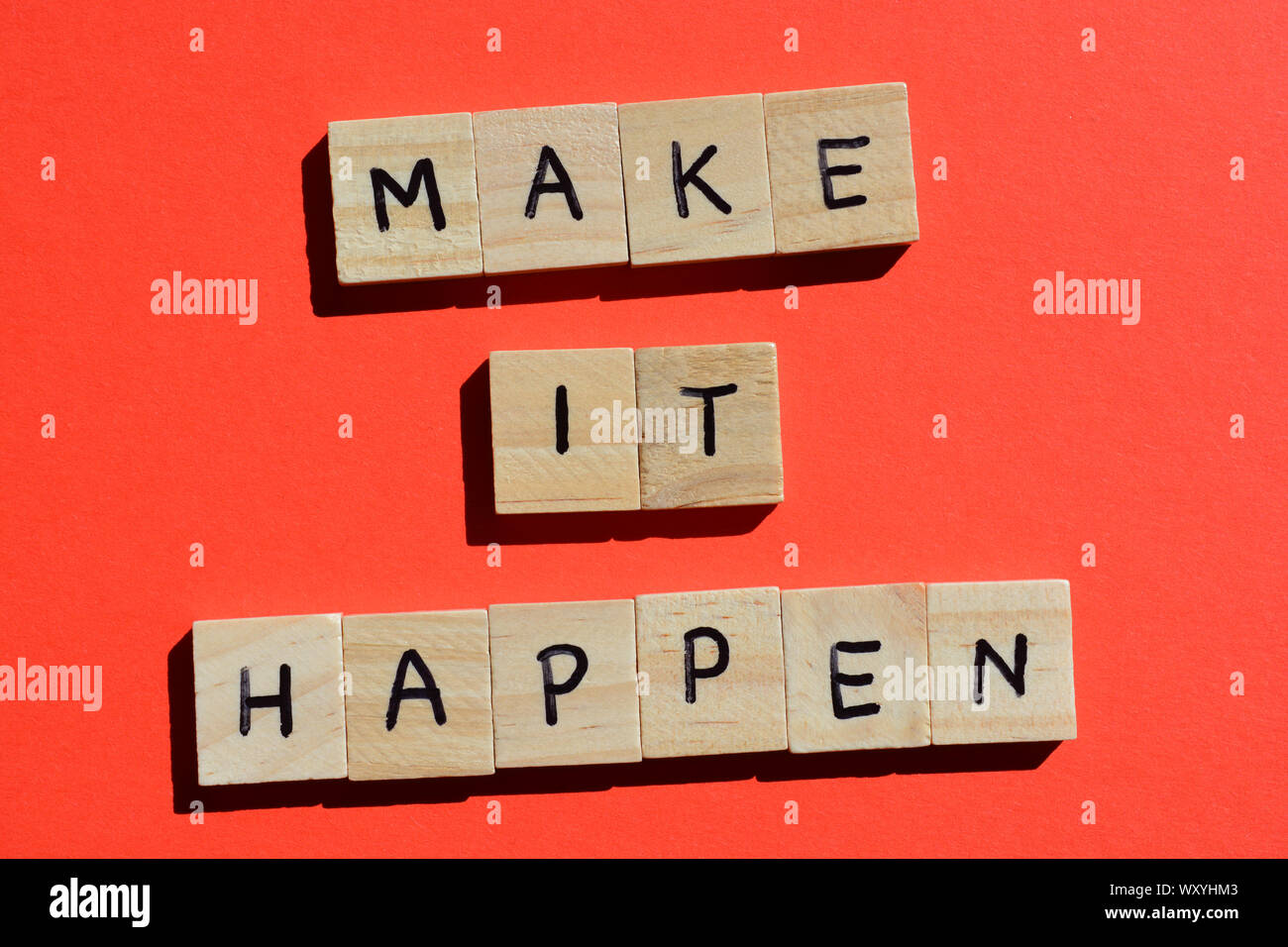 Faire se produire, de motivation citation en lettres de l'alphabet en bois sur fond rouge Banque D'Images