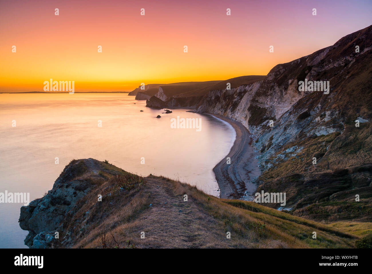 Dungy Head, Lulworth Ouest, Dorset, UK. 18 septembre 2019. Météo britannique. Ciel clair au coucher du soleil alors que le ciel devient orange vif à Dungy Head dans l'ouest de la crique de Lulworth sur la côte jurassique du Dorset en vue le long des falaises vers Durdle Door, chauves-souris et tête de Nothe blanc. Crédit photo : Graham Hunt/Alamy Live News Banque D'Images