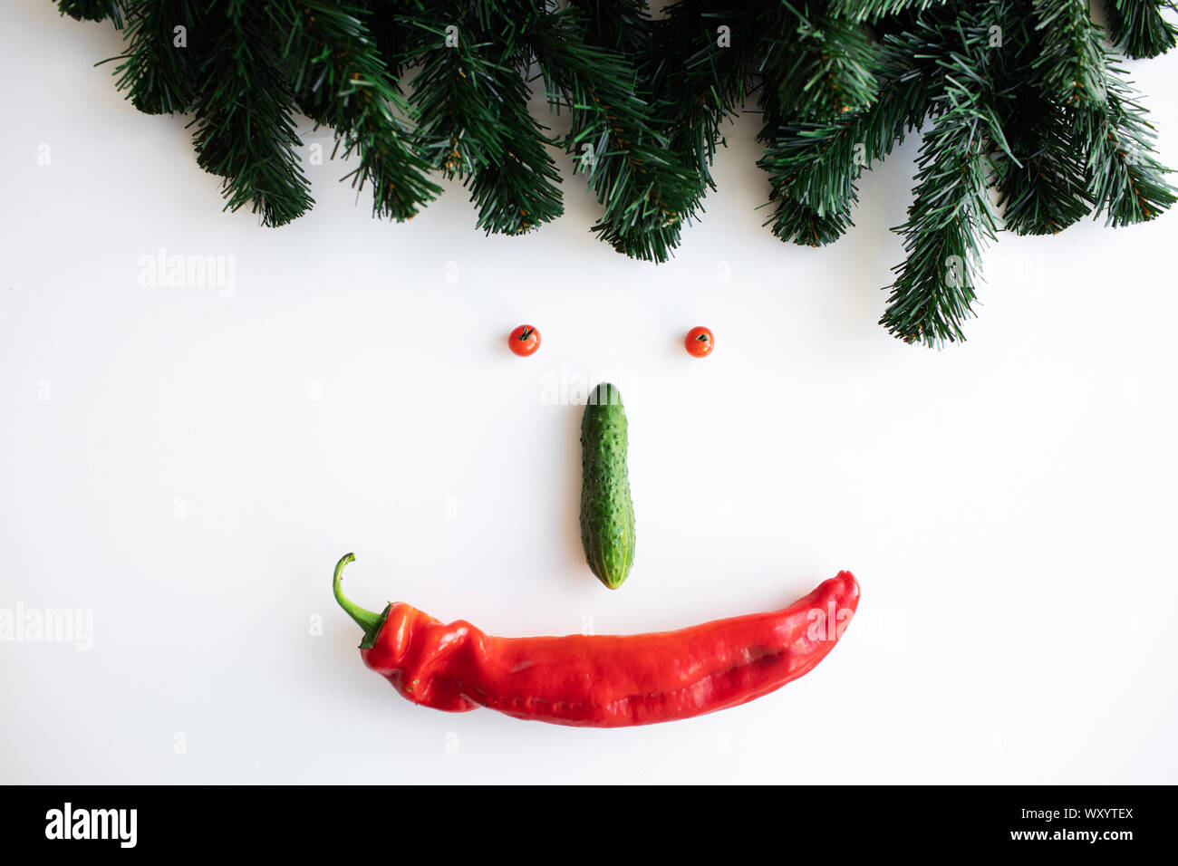 Des légumes sur la table sous la forme de smiley de poivre, de concombre, de cerise et de branches d'épinette Banque D'Images