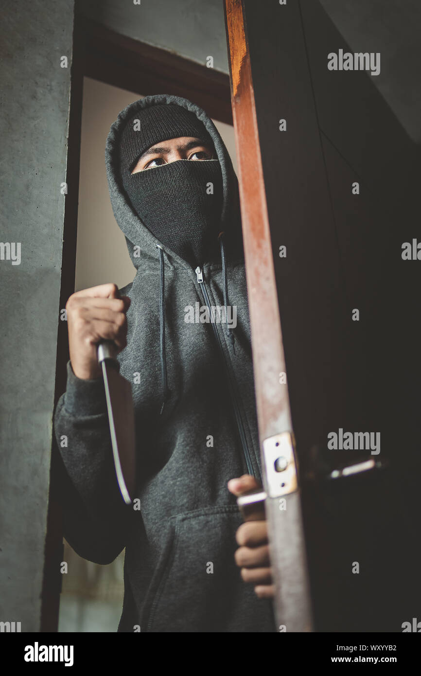 Le voleur est titulaire d'un couteau pour ouvrir la porte de la maison pour vol qualifié. Banque D'Images