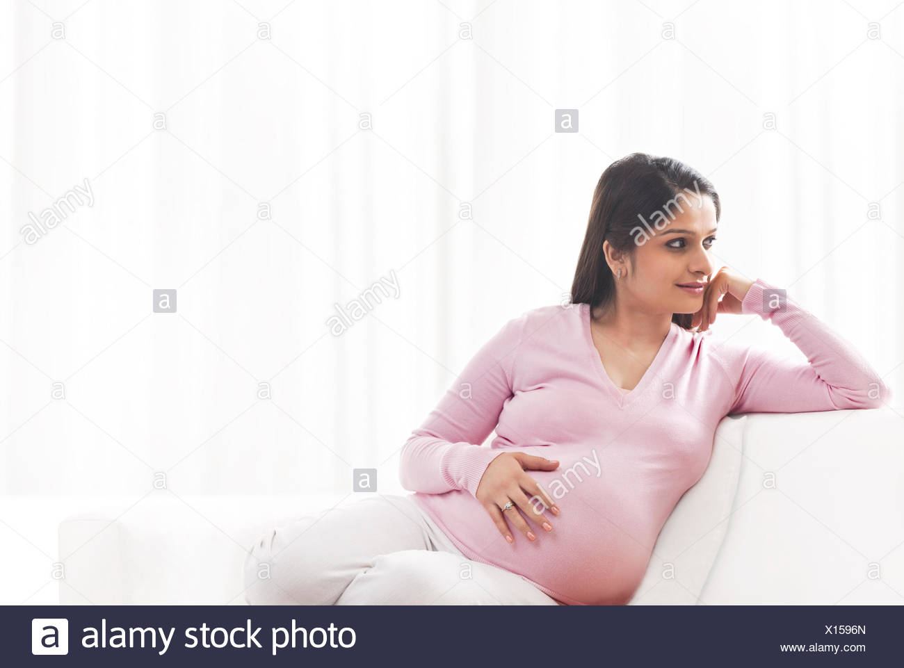 Pregnant woman sitting on a couch Banque D'Images