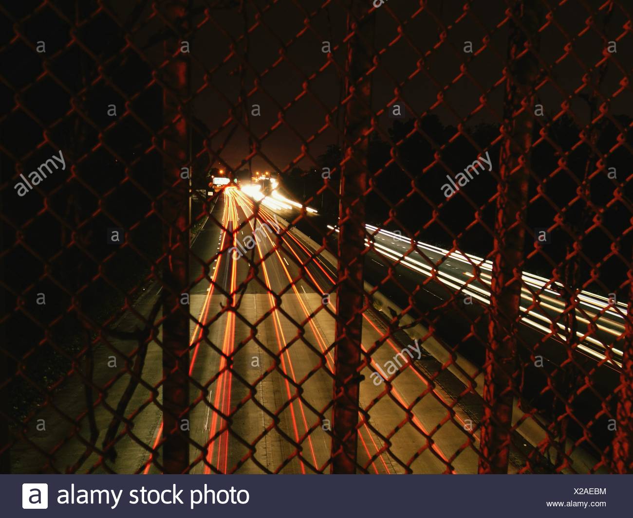 Véhicule lumineux Light Trails sur l'autoroute vu de Chainlink Fence Banque D'Images