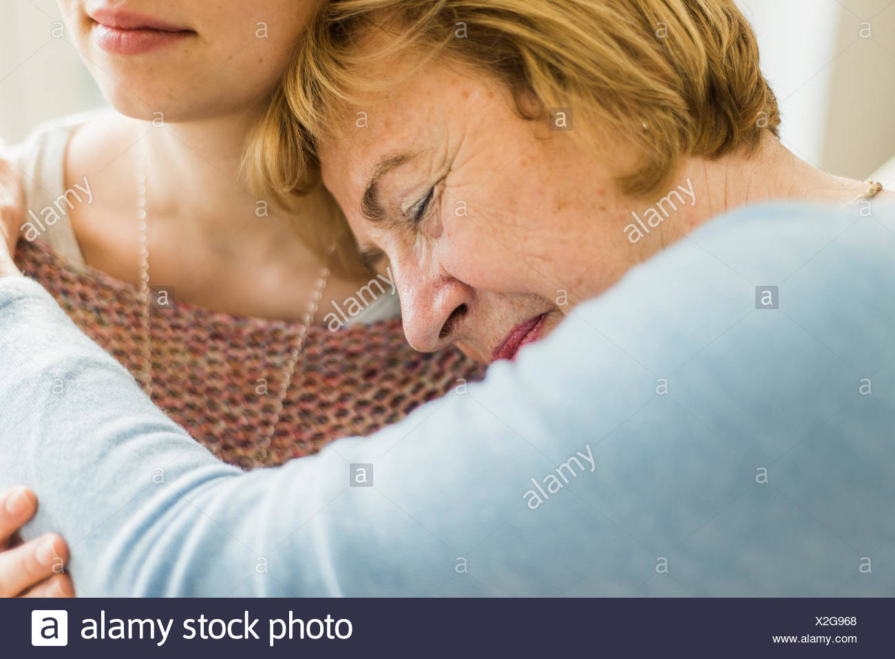 Senior woman with closed eyes appuyé contre l'épaule de la jeune femme Banque D'Images