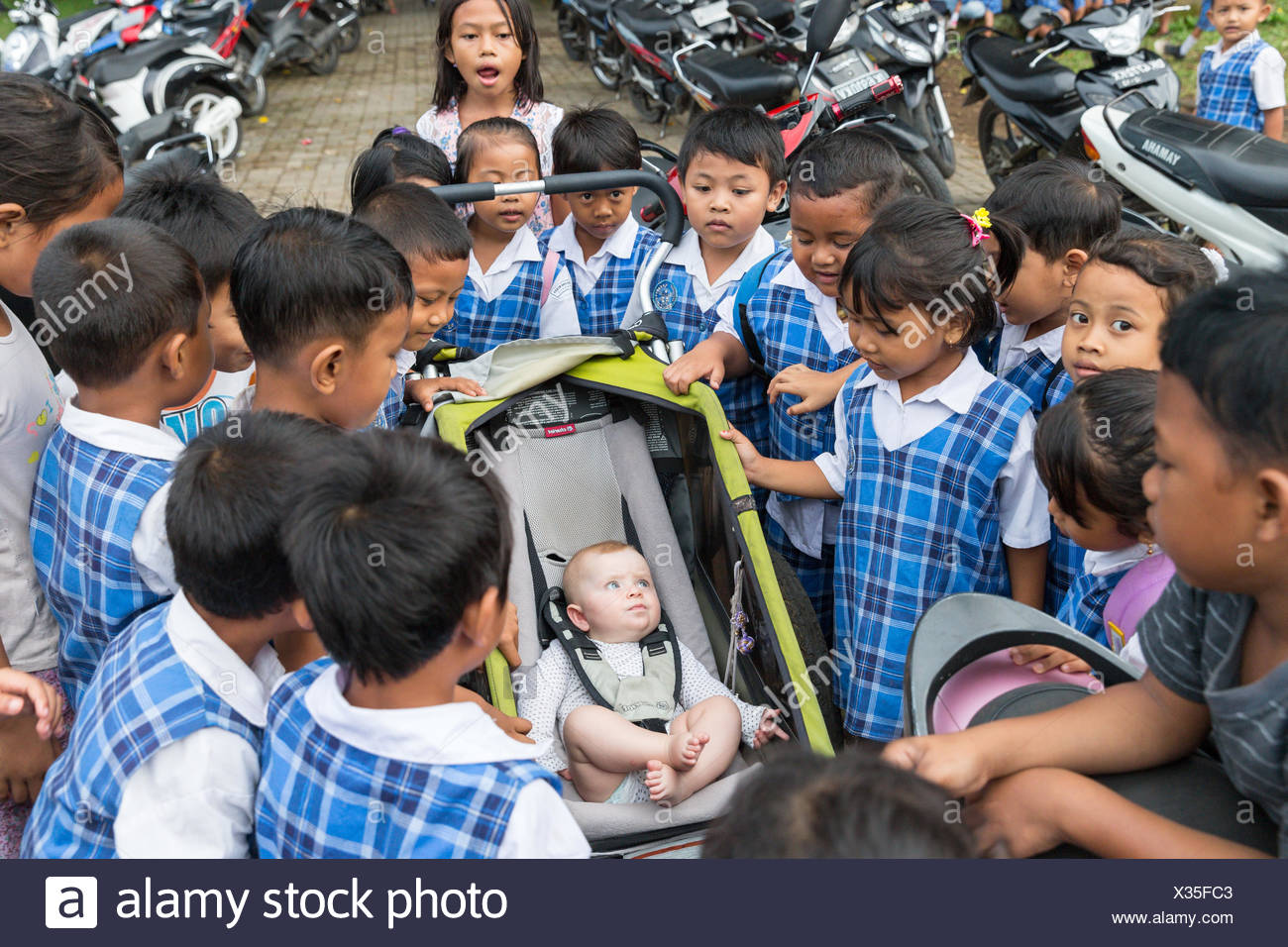 De Nombreux Ecoliers Balinais Etre Curieux Au Sujet De L Ouest Bebe Fille 5 Mois Assis Dans Une Poussette Pour Les Enfants Autour De La Collecte Photo Stock Alamy