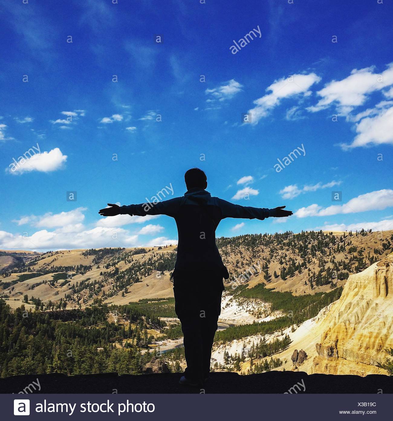 Vue arrière de l'Homme debout, les bras tendus par les montagnes Against Sky Banque D'Images