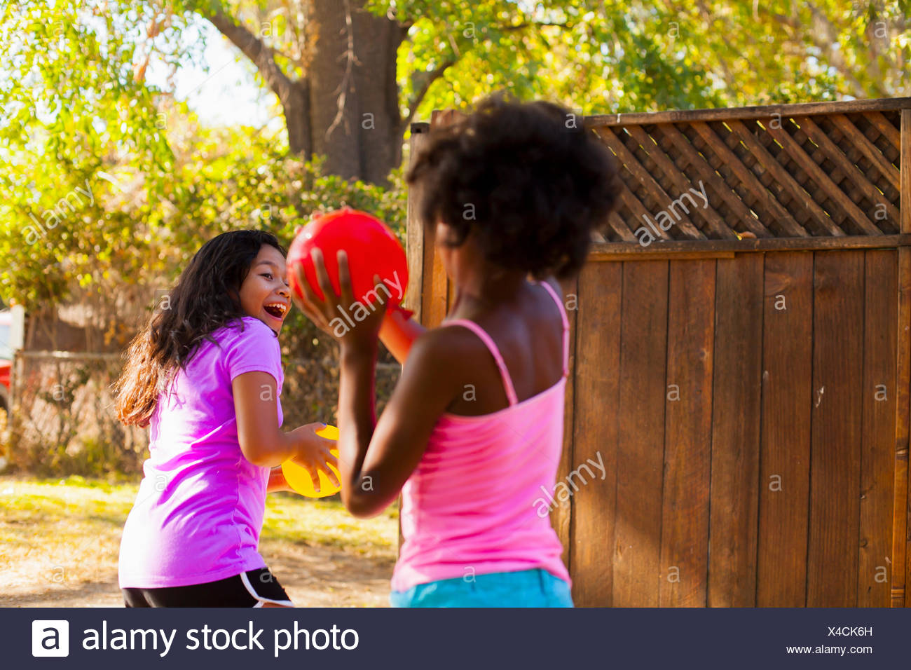 Girl chasing ami ballon avec de l'eau dans le jardin Banque D'Images