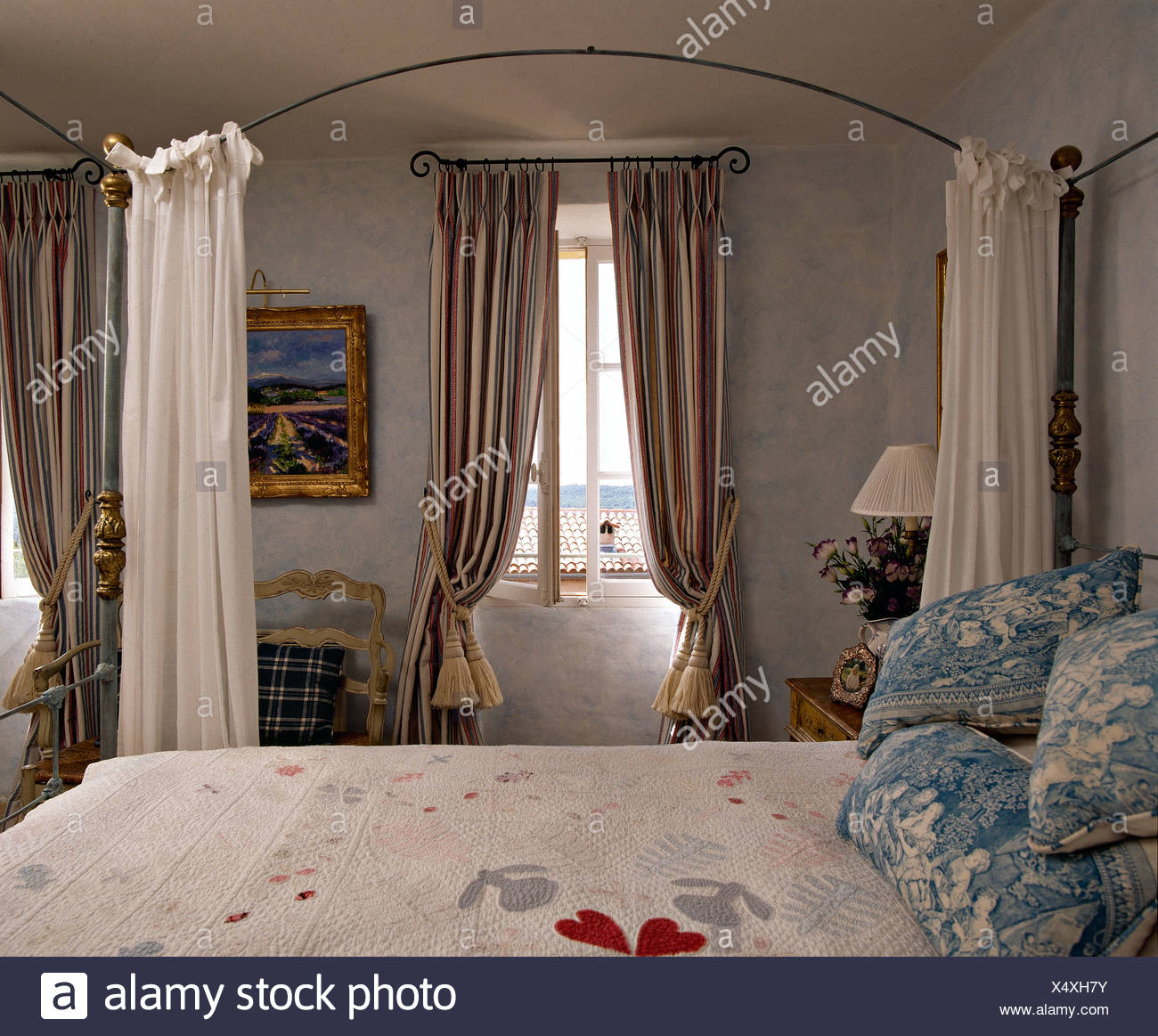 Blanc Et Bleu Coussins Patchwork Pale Sur Un Lit A Baldaquin En Metal Francais Pays Chambre Avec Rideaux Rayes Dans Windows Photo Stock Alamy