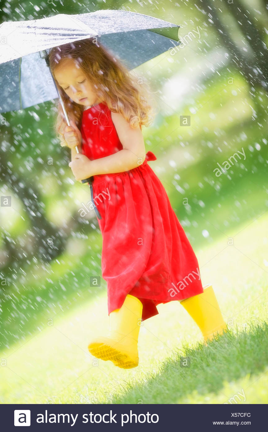 Une Petite Fille Qui Marche Sous La Pluie Dans Une Robe Rouge Tenant Un Parapluie Photo Stock Alamy