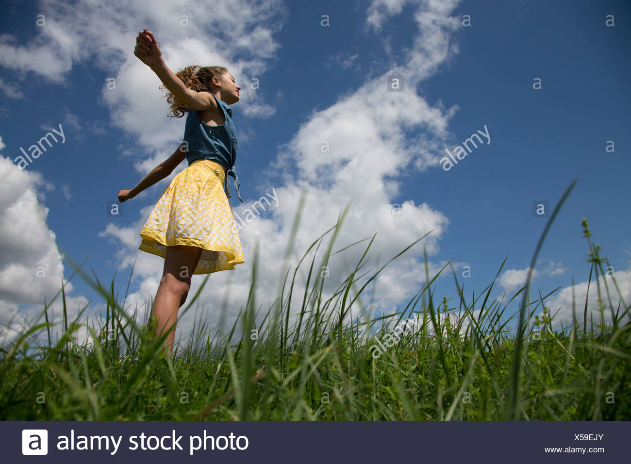 Teenage Girl standing with arms outstretched in field Banque D'Images