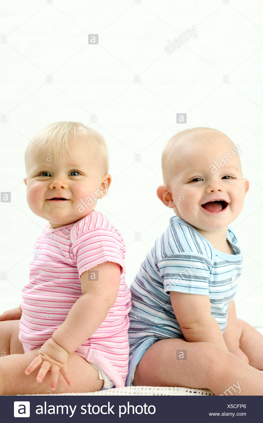 Deux Bebes Assis Dos A Dos Bebe Male A Gauche Wearing Blue Striped Babygro A Rire A L Appareil Photo Les Femmes Du Baby Sur Photo Stock Alamy