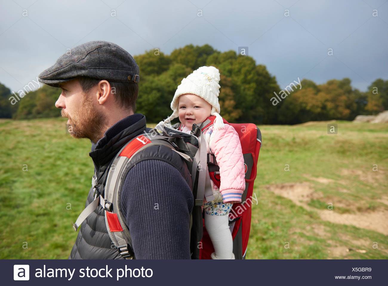 Vue Laterale Du Champ De Man Wearing Flat Cap Portant Sur Fille En Porte Bebe Photo Stock Alamy