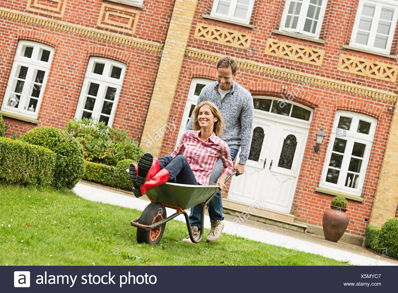 Mid adult man pushing woman in brouette Banque D'Images