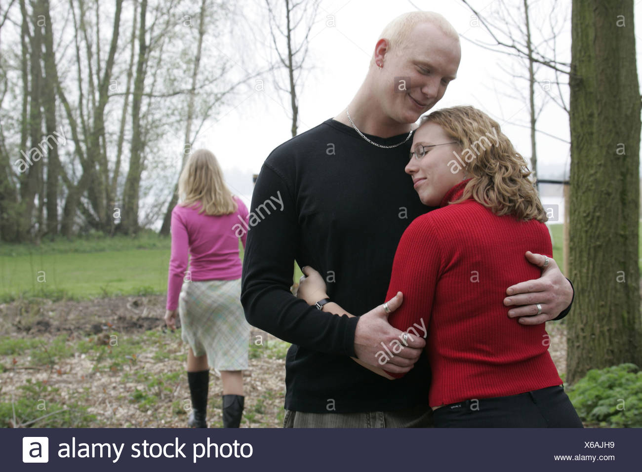 Jeune femme MARCHE LOIN DE COUPLE HUGGING EXTÉRIEUR. Banque D'Images