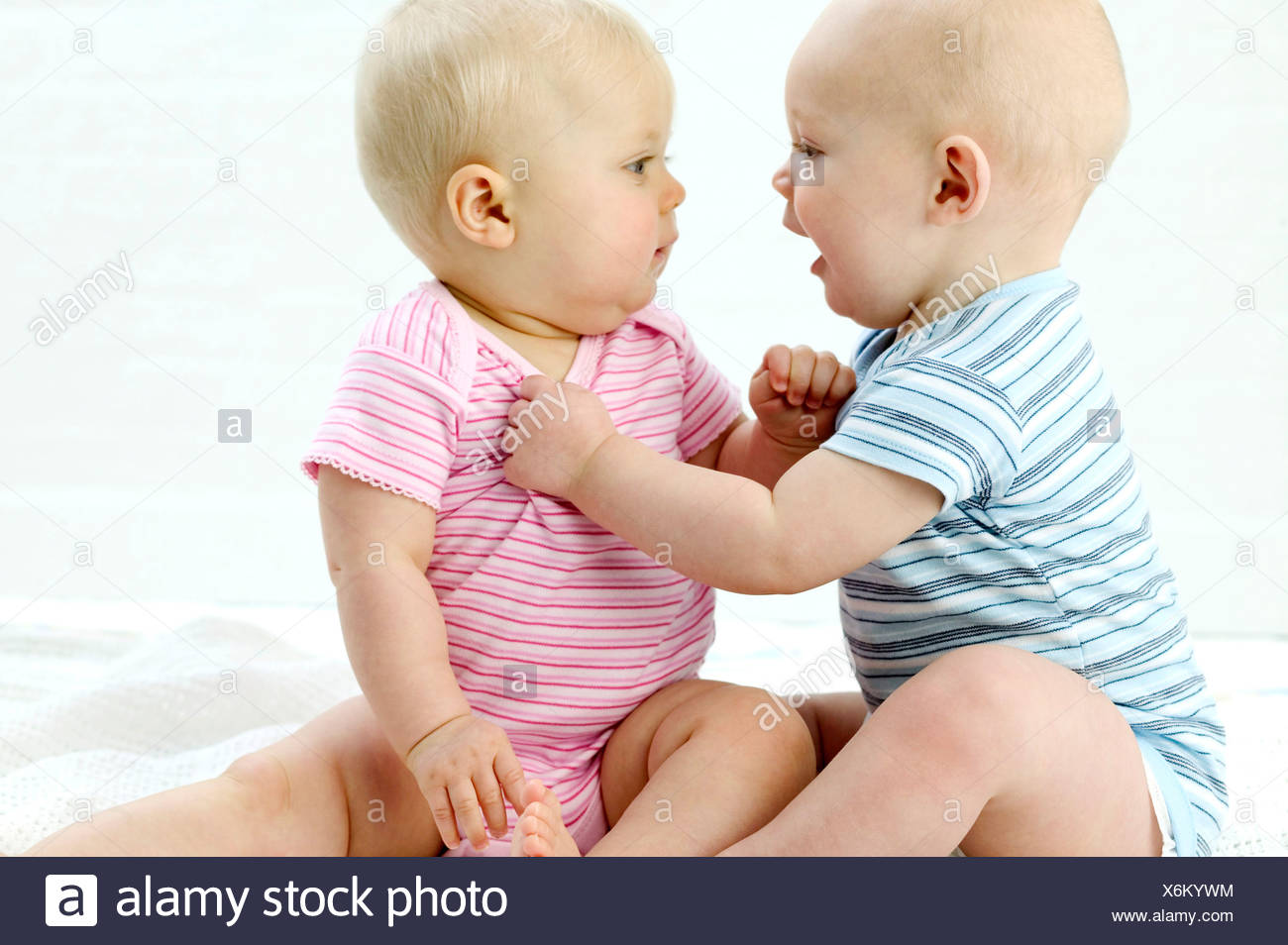 Deux Bebes Se Regardant Sourire Bebe Male A Gauche Wearing Blue Striped Babygro En Maintenant Les Autres Bebes Haut Femme Photo Stock Alamy