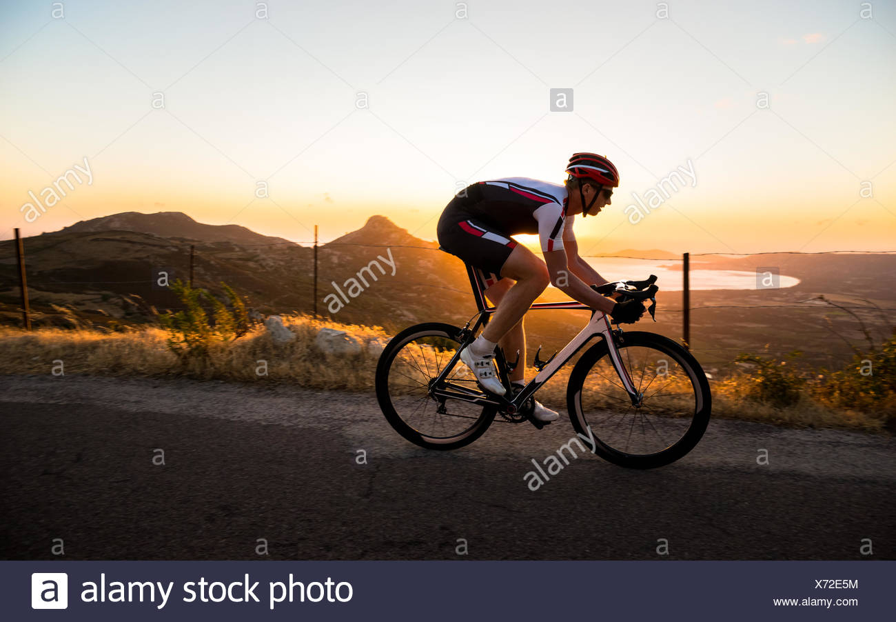 Homme randonnée à vélo au coucher du soleil, Corse, France Banque D'Images