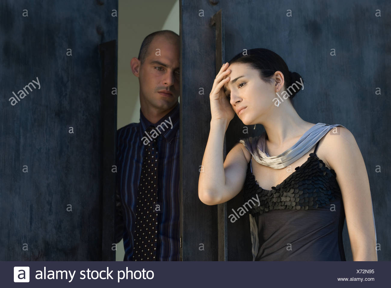 Couple standing in doorway, woman holding head, les deux à la voiture Banque D'Images