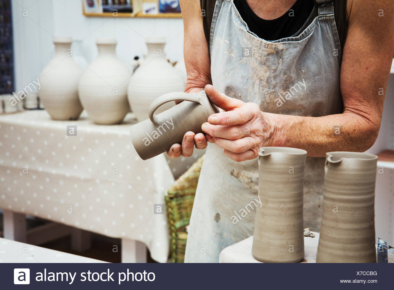 Un potter de la manipulation d'un pot d'argile humide, le lissage de la partie inférieure et la préparer pour la cuisson au four. Banque D'Images