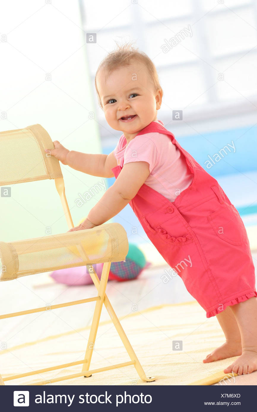 Bebe 9 Mois Sourire Tenir Sur Une Chaise Debout Photo Stock Alamy