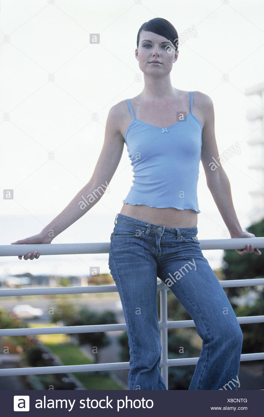 Balcon, femme, debout, voir l\u0027appareil photo, détail, 30,40 ans, aux cheveux bruns, jeans, top, ventre nu, fashion, mode, style, sourire, l\u0027assurance,