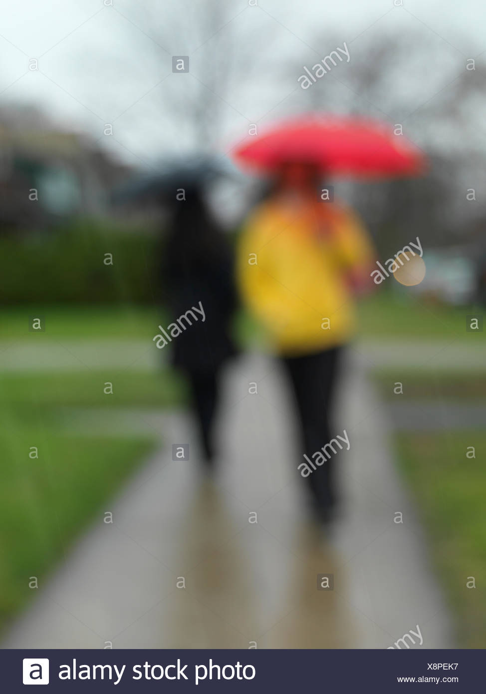 Les gens avec des parasols sur un trottoir sous la pluie, blurred Banque D'Images
