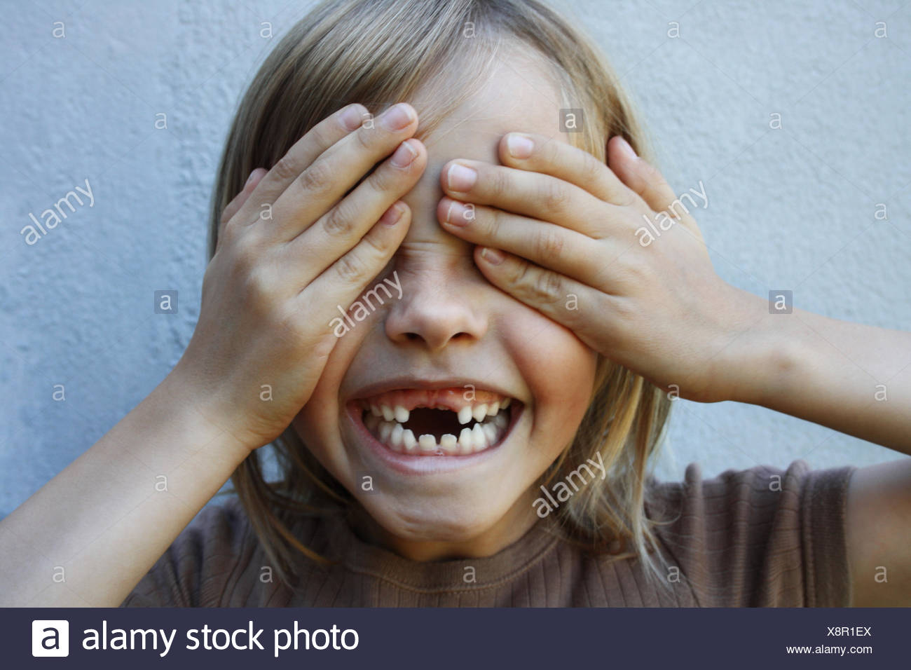 Avec gap garçon sourire denté avec mains couvrant les yeux Banque D'Images