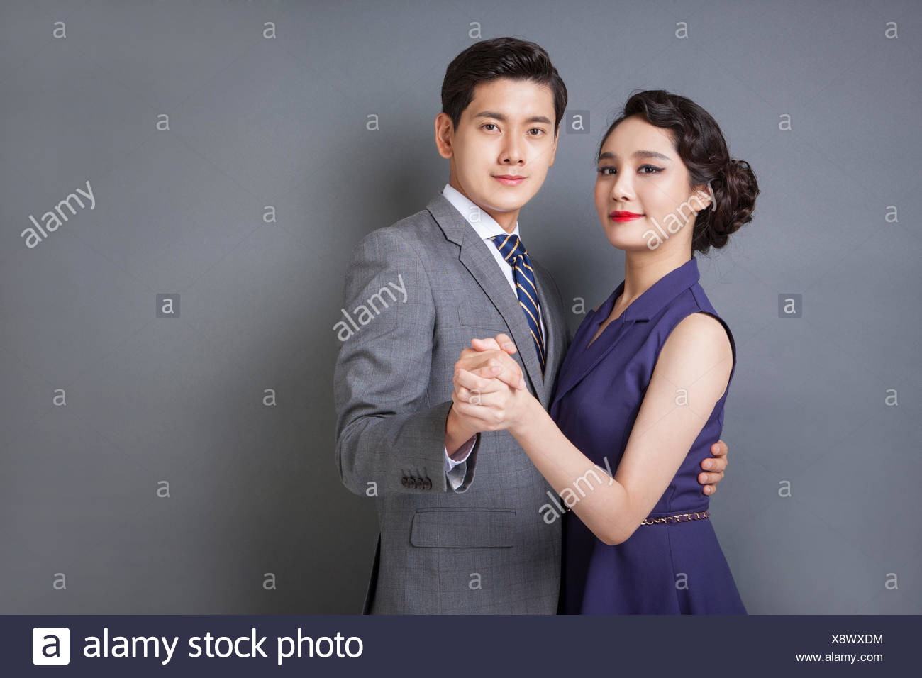 L'homme en costume et cravate dans un style rétro et une femme en robe de  style rétro se tenant la main et dansant ensemble Photo Stock - Alamy