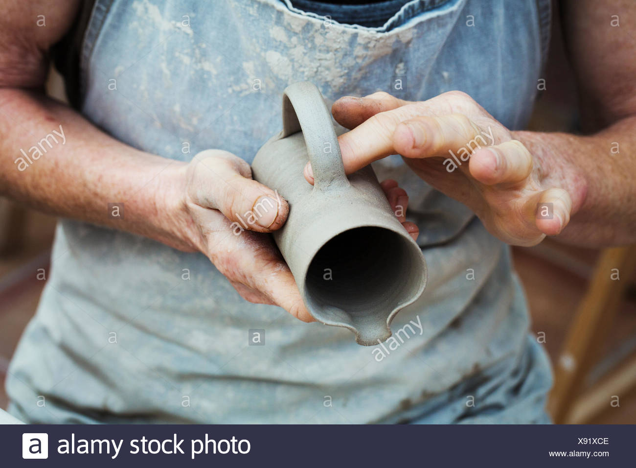 Un potter de la manipulation d'un pot d'argile humide, le lissage à l'extérieur et la préparer pour la cuisson au four. Banque D'Images