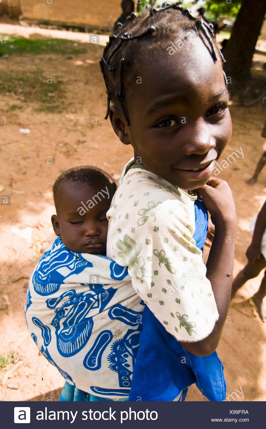 Une Fille Mignonne Du Burkina Faso D Enfant Portant Son Bebe Sur Son Dos Photo Stock Alamy
