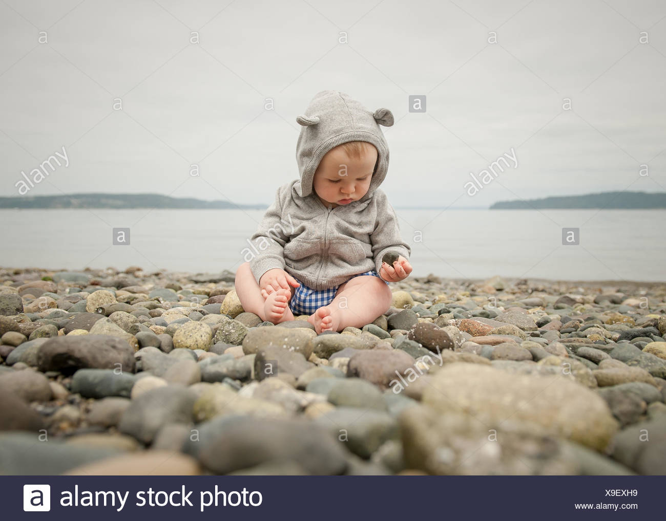 Bebe Garcon Assis Sur Une Plage Jouer Avec Des Cailloux Photo Stock Alamy