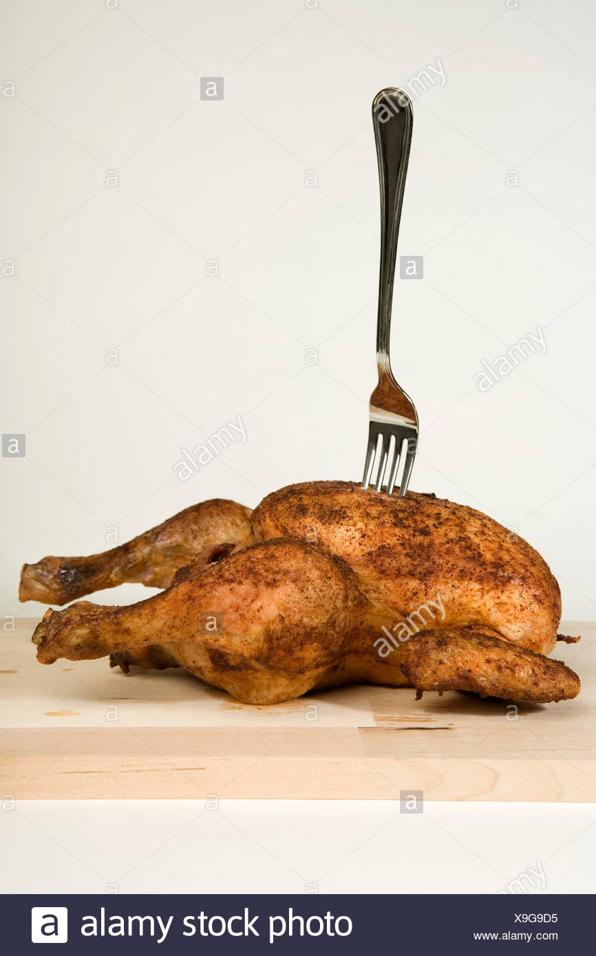 Une fourchette coincé dans un poulet rôti Banque D'Images