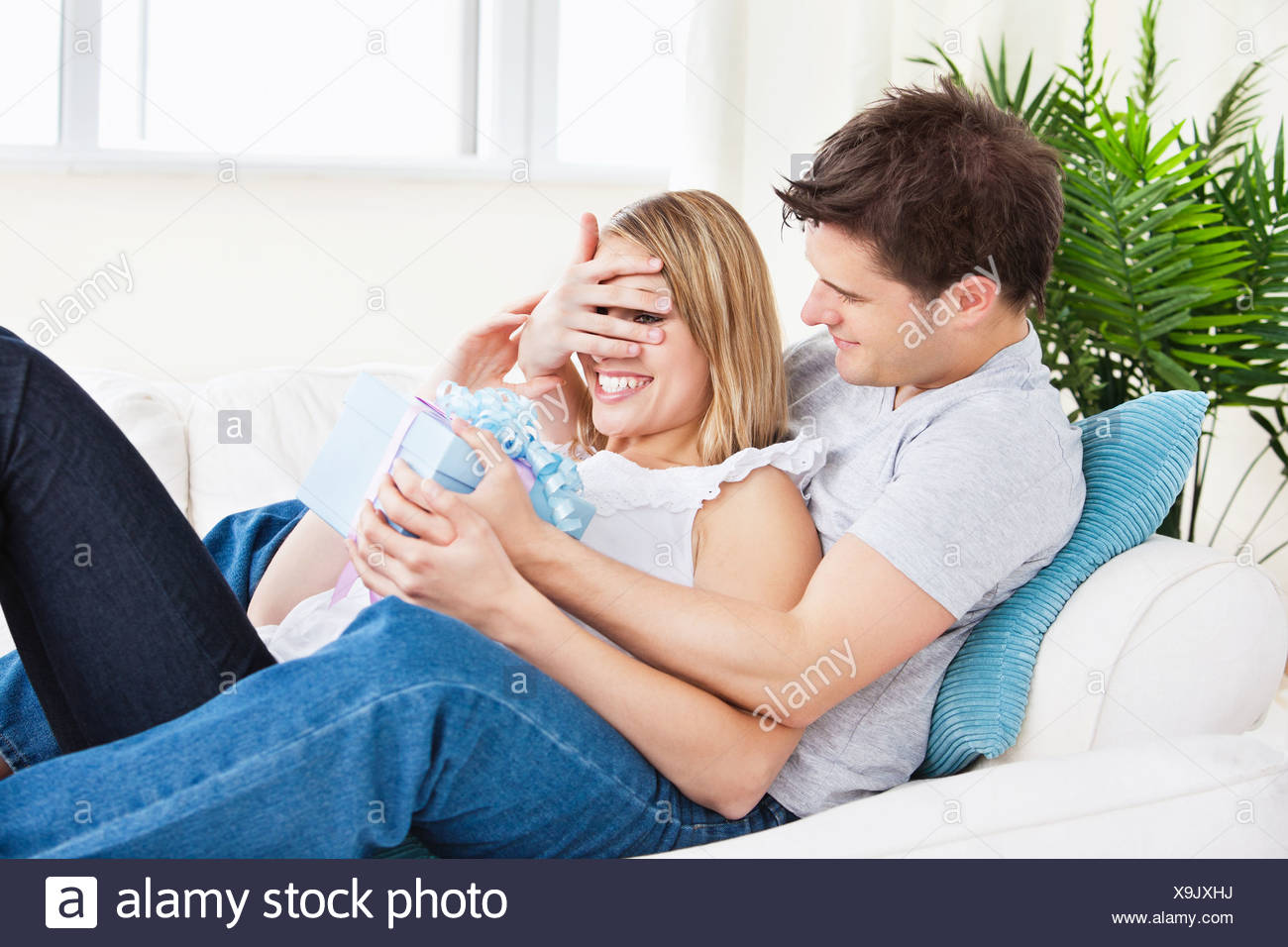 Jeune Couple Allonge Sur Le Canape Avec Un Present Banque D Images