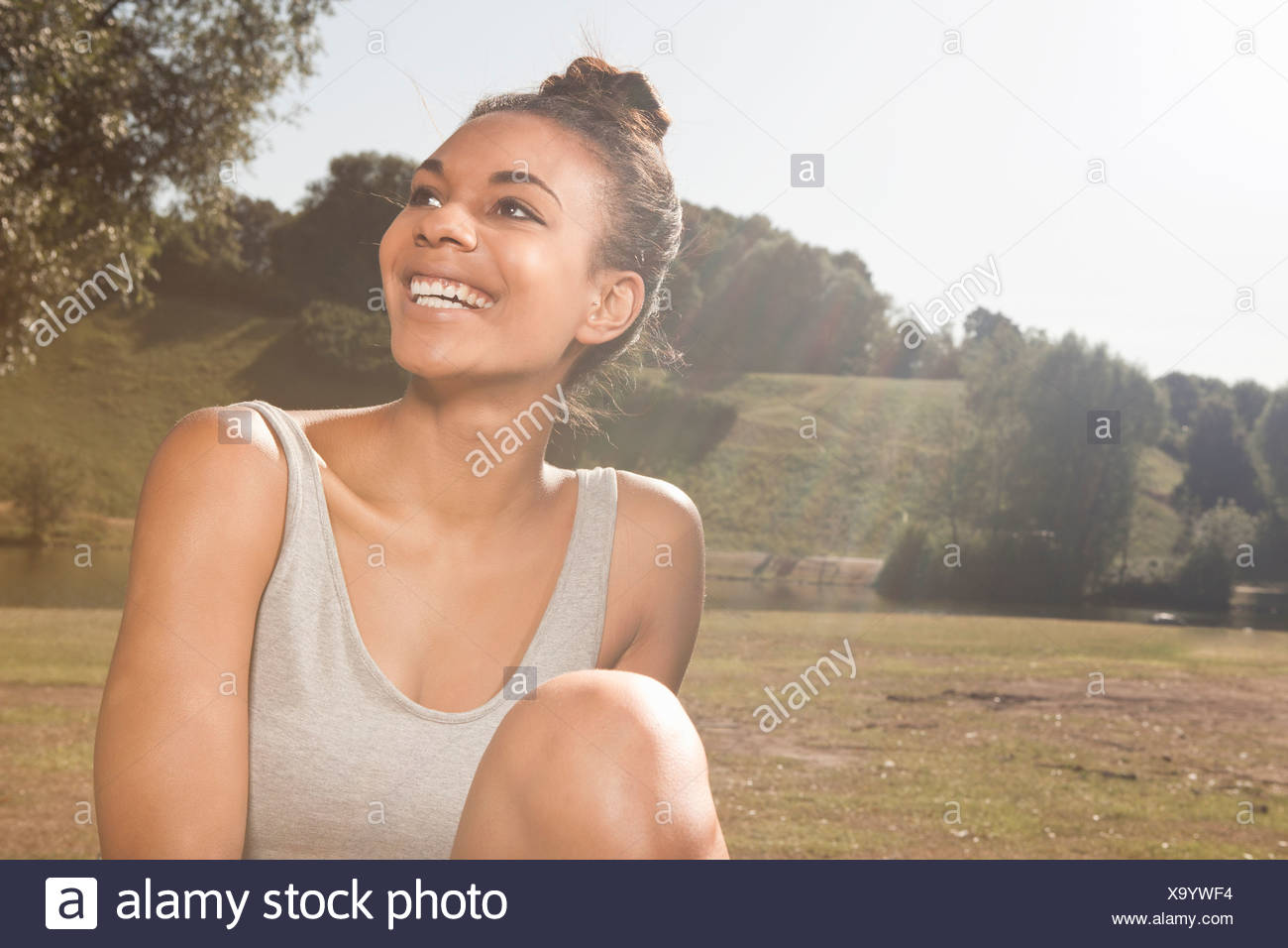 Jeune femme heureuse dans la lumière du soleil dans un parc Banque D'Images