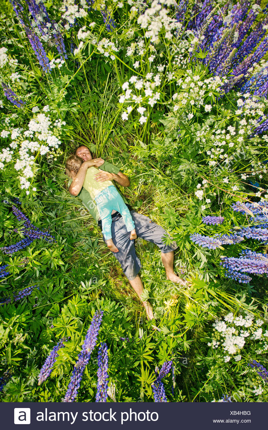 La Finlande, man and girl (2-3) lying in meadow Banque D'Images