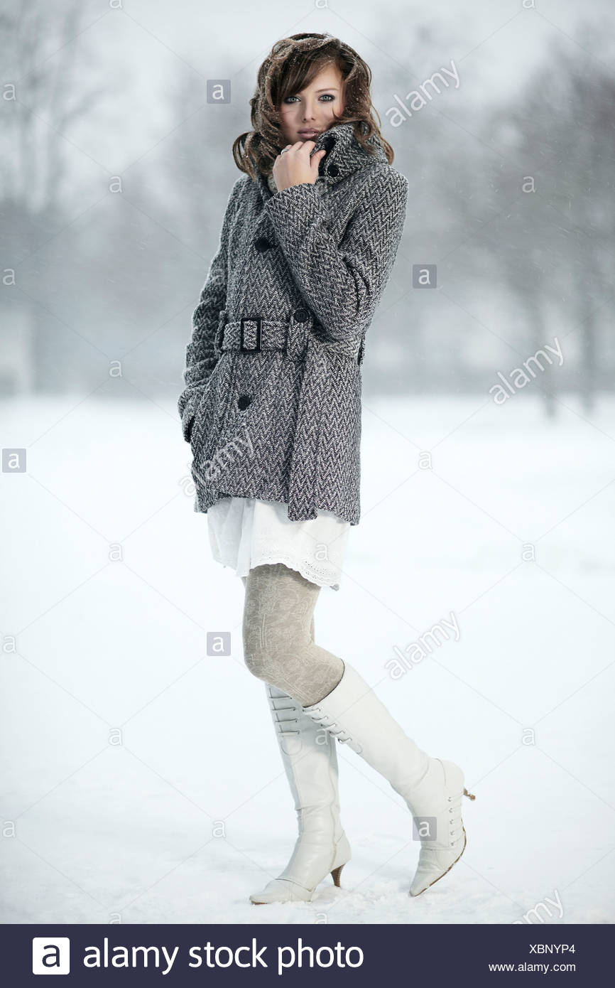 Portrait d'une jeune femme dans la neige, sa main tenant son collier manteau Banque D'Images