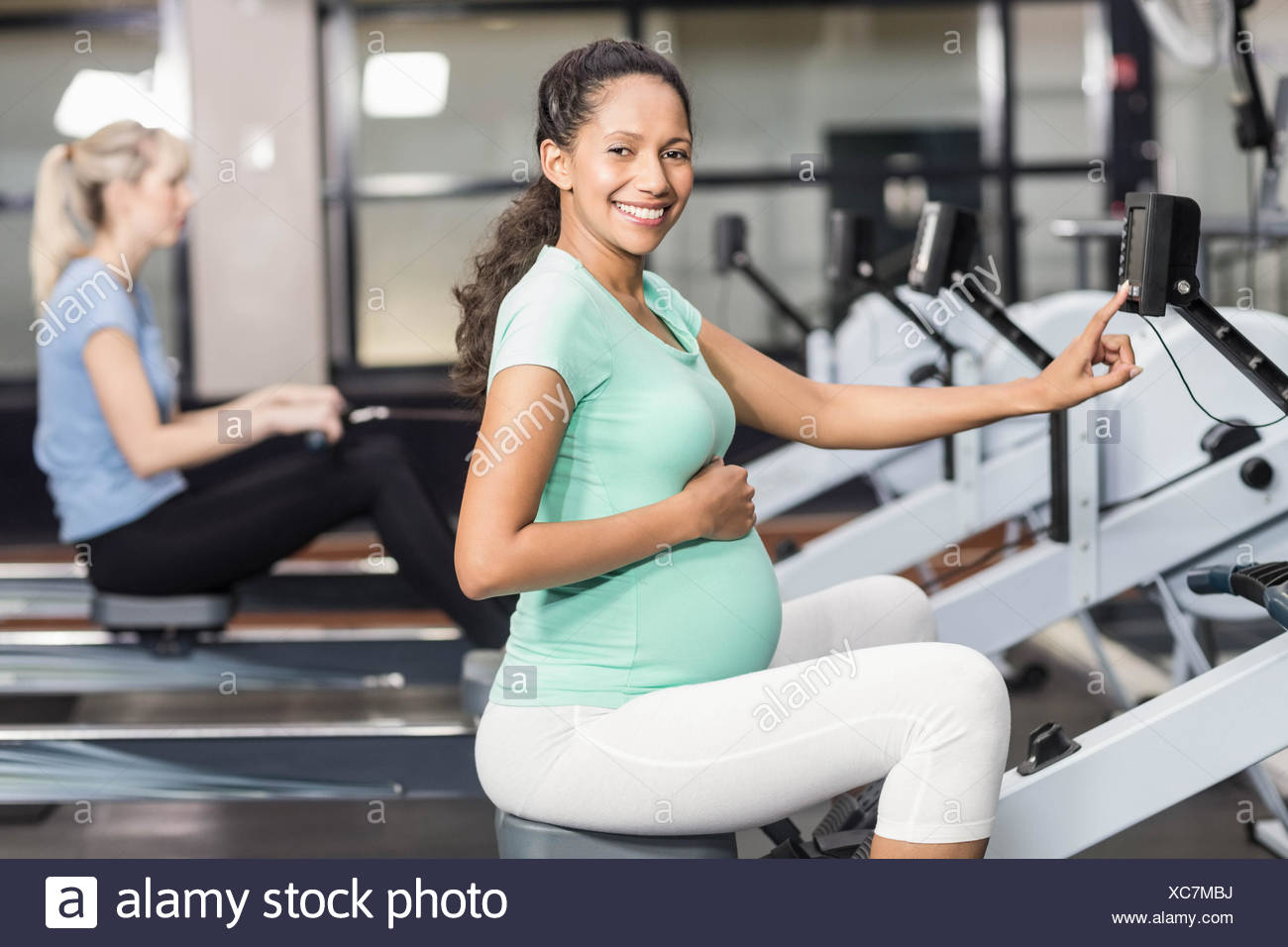 Femme enceinte l'exercice et à la recherche à l'appareil photo Banque D'Images