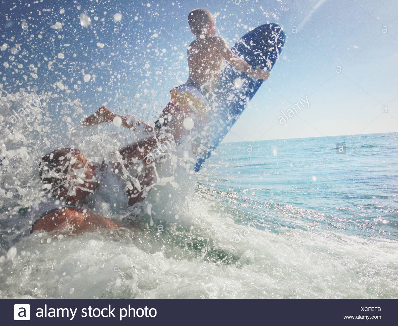 Père et fils jouant dans l'océan avec planche de surf, Californie, États-Unis Banque D'Images