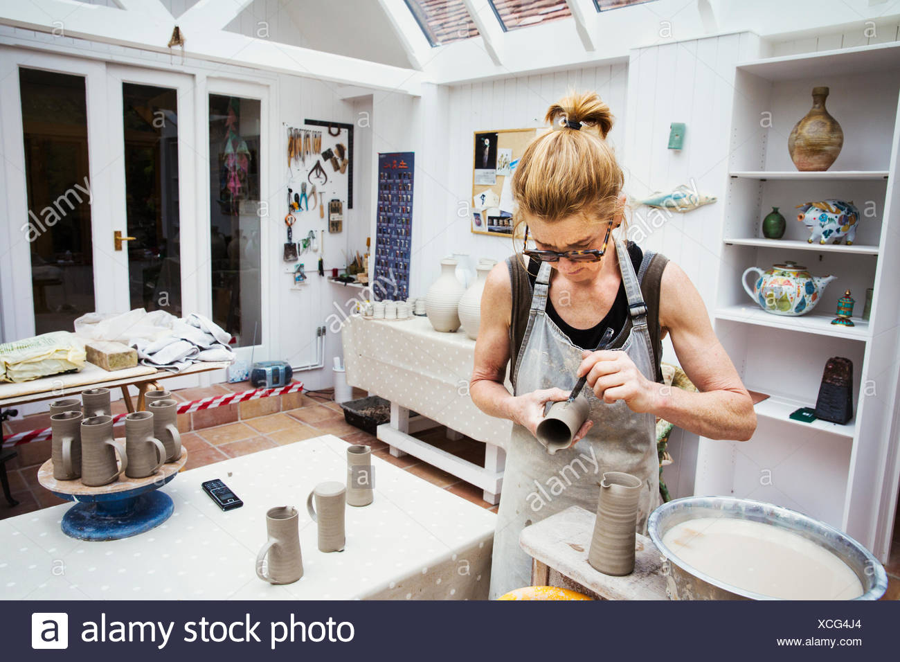 Un potter de la manipulation d'un pot d'argile humide, en lissant les bords et la préparer pour la cuisson au four. Banque D'Images