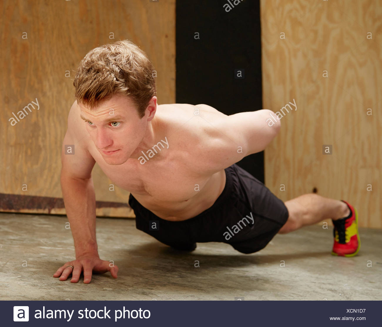 Mid adult male faisant l'un des pousées in gym Banque D'Images
