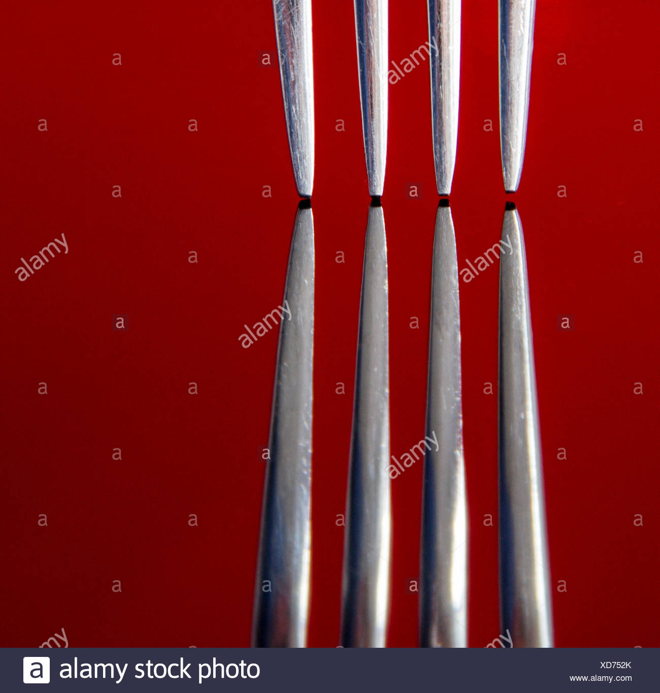 Close up de dents de fourche sur une surface réfléchissante rouge, studio shot Banque D'Images