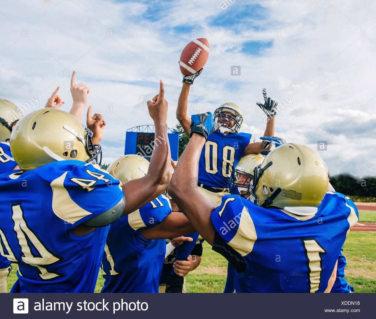Les adolescentes et les jeunes équipes de football américain célébrant la victoire sur terrain de football Banque D'Images
