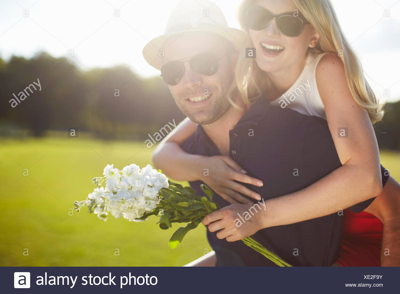 Jeune femme avec des fleurs se greffer de copain dans park Banque D'Images