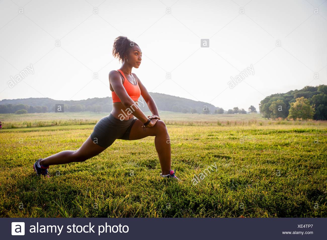Young female runner stretching en parc rural Banque D'Images