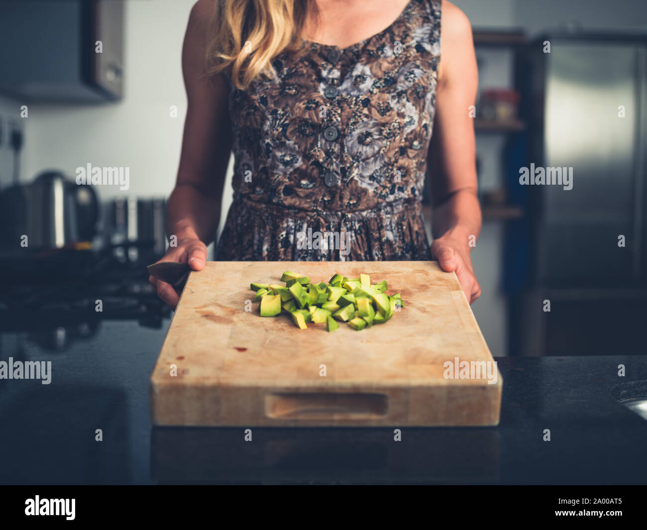 Una giovane donna è la trinciatura avocado nella sua cucina moderna Foto Stock