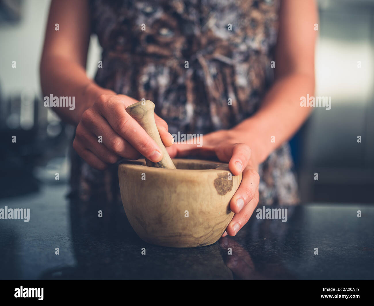 Una giovane donna con un pestello e mortaio nella sua cucina Foto Stock
