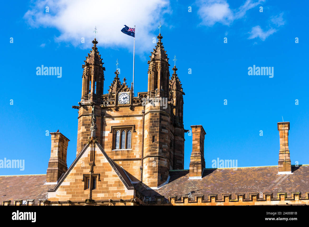 Sydney Uni facciata di edificio con bandiera australiana. Università di Sydney contro profondo cielo blu con nuvole bianche, diurno foto Foto Stock