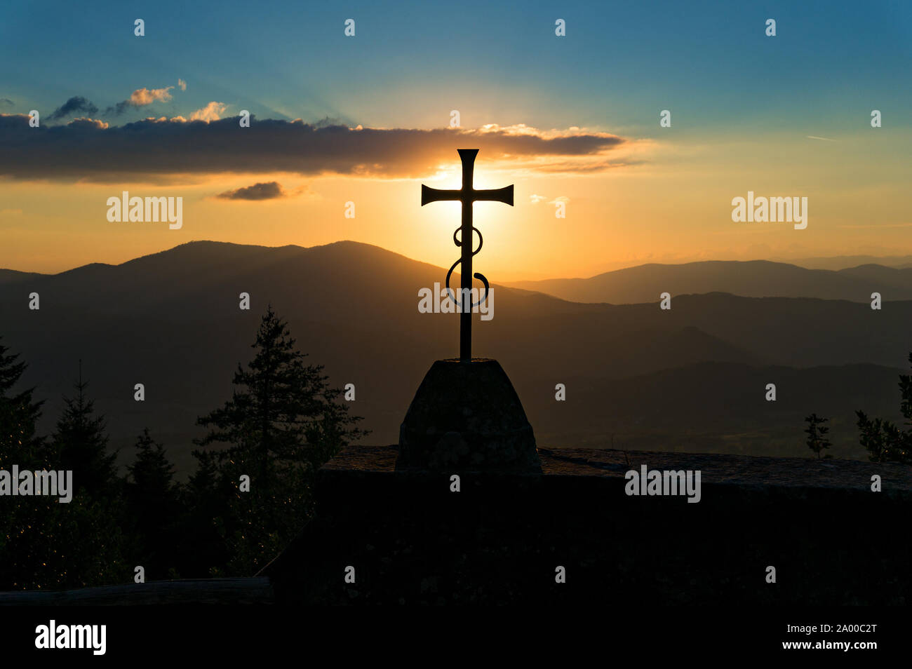 Una croce cristiana con il tramonto e le colline. Simbolo religioso contro lo sfondo della natura Foto Stock